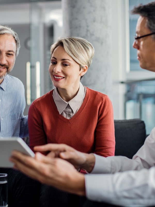 happy-mid-adult-couple-using-touchpad-with-their-financial-consultant-in-the-office